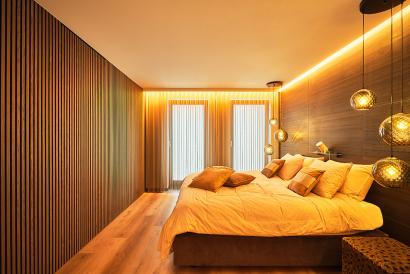 Moderne kamer met houten plintjes tegen de muur, led-strip met warm wit licht en een mat-wit Plameco spanplaplafond met hanglamp.